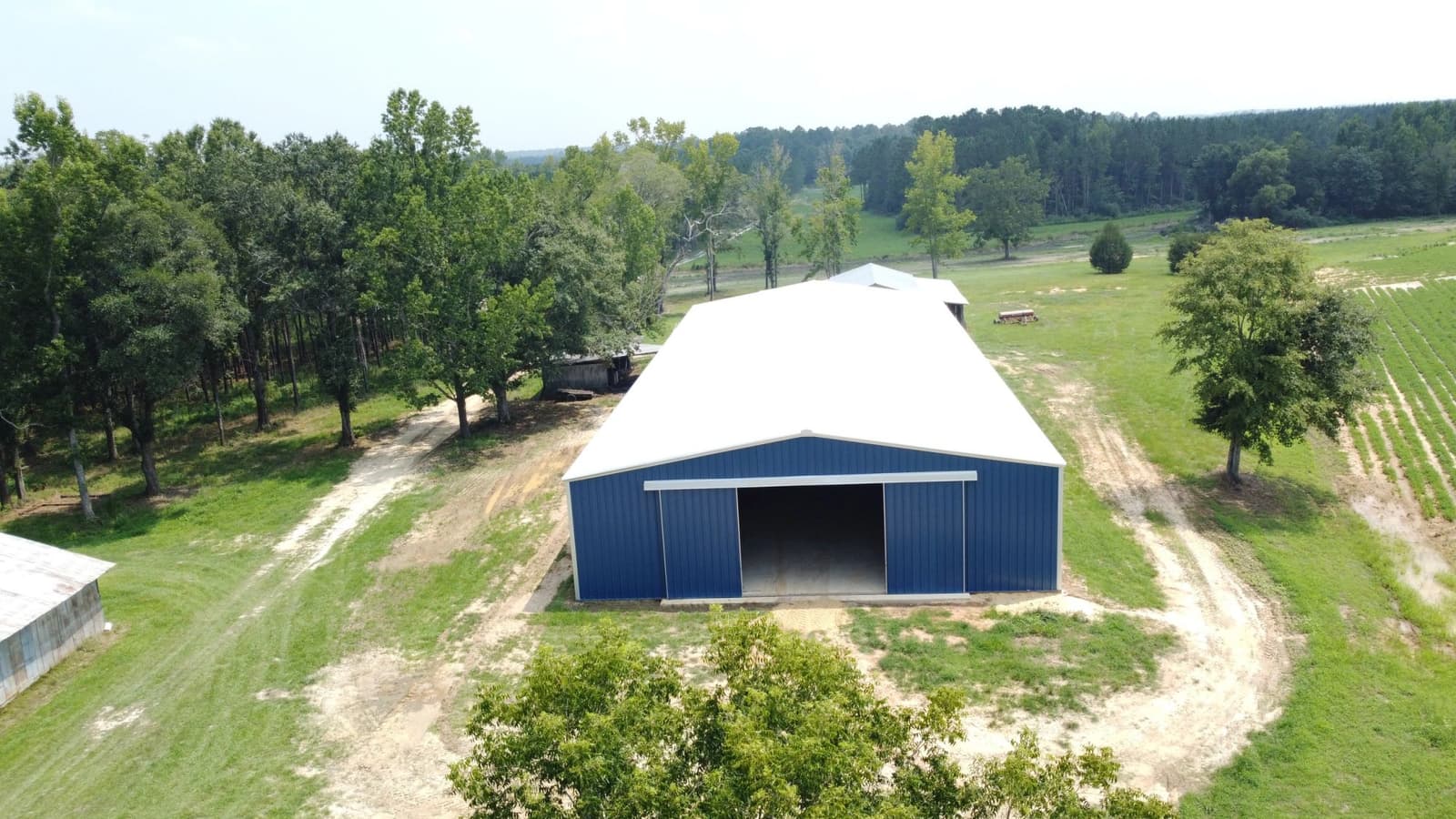 Aerial view of a blue and white metal barn in a green pasture