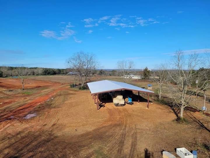 Aerial view of an open-sided farm pavilion on red clay
