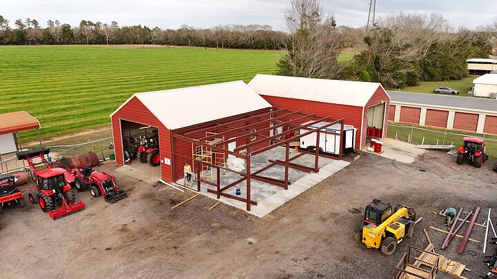 Aerial view of red iron framing for a building addition beside a red shop