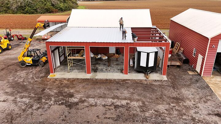 Aerial view of a crew roofing a red metal building addition