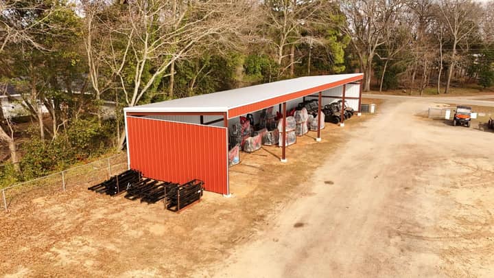 Aerial view of a red-sided open equipment shed at the edge of the woods