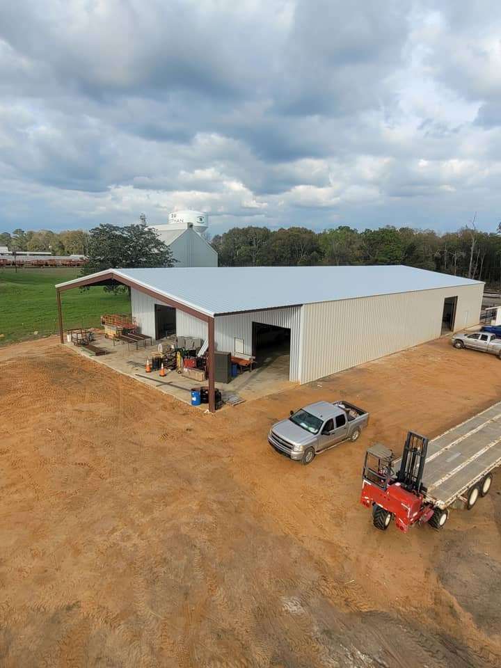 Aerial view of a white shop building with lean-to and equipment trailer