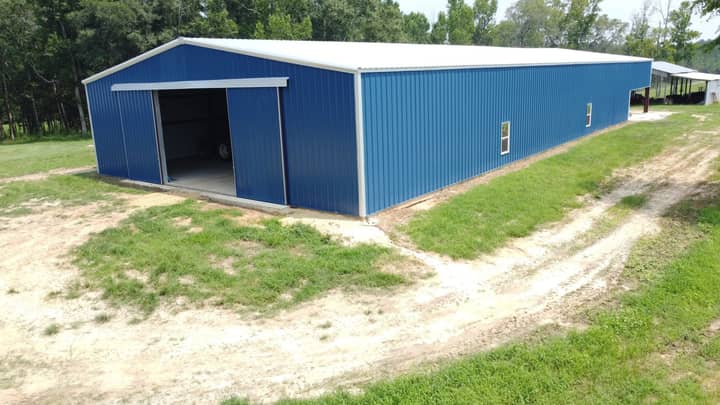 Blue metal barn with white roof and large open doors
