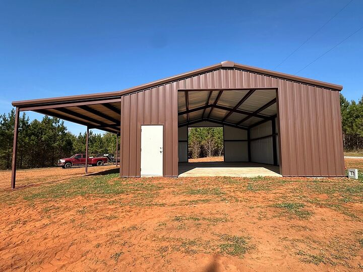 Brown metal shop with an open drive-through bay and a side lean-to