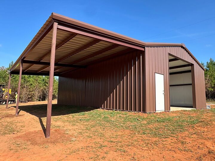 Brown metal building with a long open lean-to on red clay