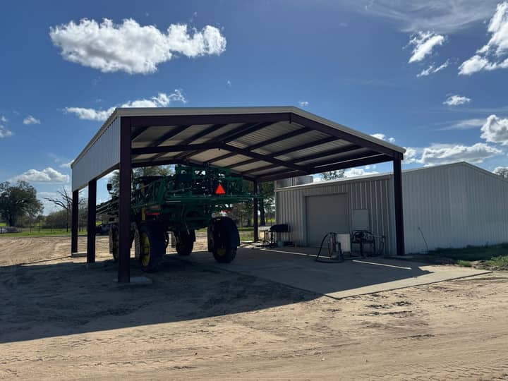 Tall open equipment shed beside a steel shop building