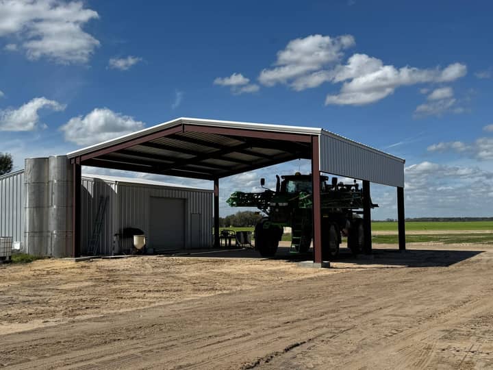 Open-front steel equipment shed with a high-clearance sprayer