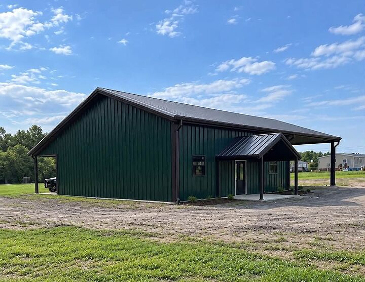 Green metal building with a covered side entry and a lean-to porch