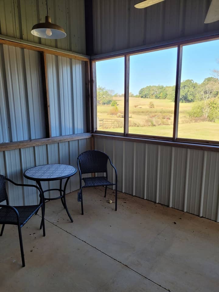 Screened porch inside a metal home overlooking a pasture