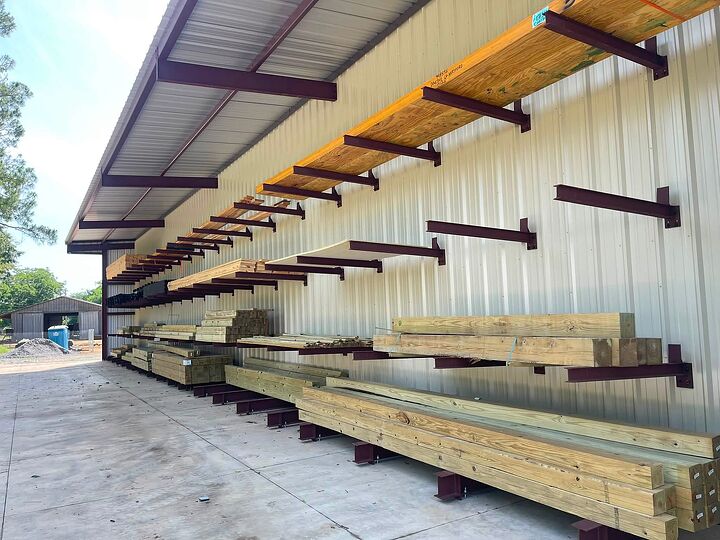 Tan metal building with a covered lean-to over outdoor lumber racks