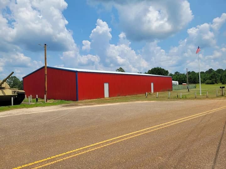 Red metal barn beside a two-lane road