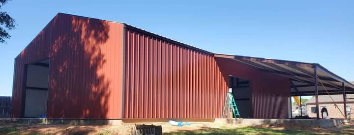 Red metal building with lean-to nearing completion