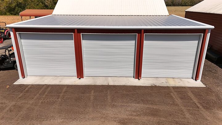 Red metal building with three white roll-up doors seen from above