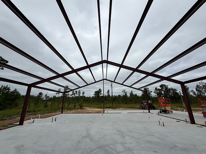Looking up through red iron rafters and purlins over a new slab