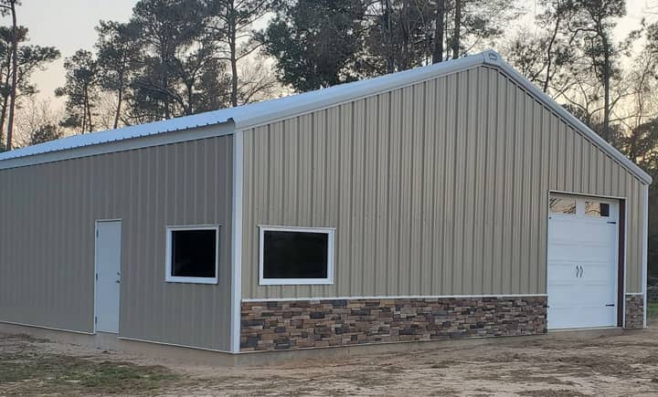 Metal shop with stone wainscot, windows, and white roll-up door