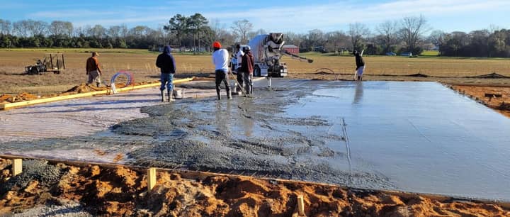 Crew finishing a large concrete slab pour for a metal building