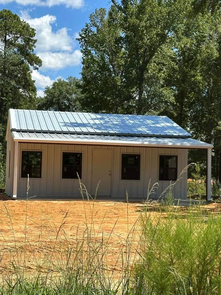 Small tan metal cabin with a covered front porch