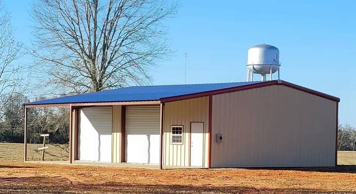 Small commercial metal building with blue roof near a water tower