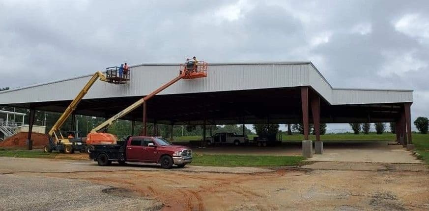 Crew on boom lifts erecting a large open-span steel building