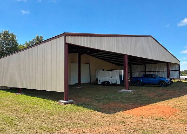 Tan open-sided equipment shed with red steel columns and enclosed storage at the back