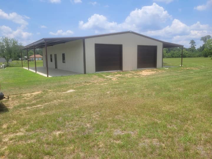 Tan metal shop with brown roll-up doors and a lean-to