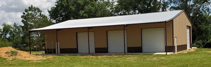 Tan metal garage with three roll-up doors and a side lean-to