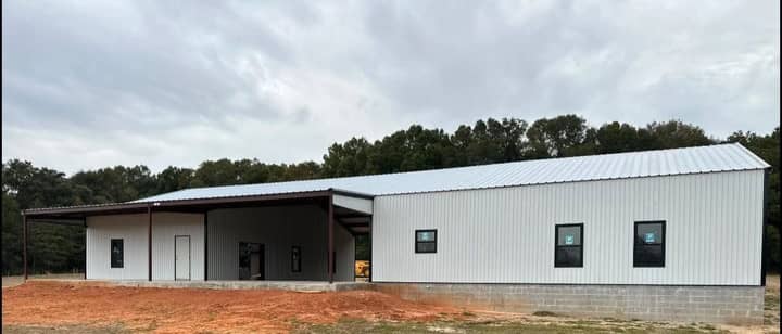 White metal home with a covered porch and black windows
