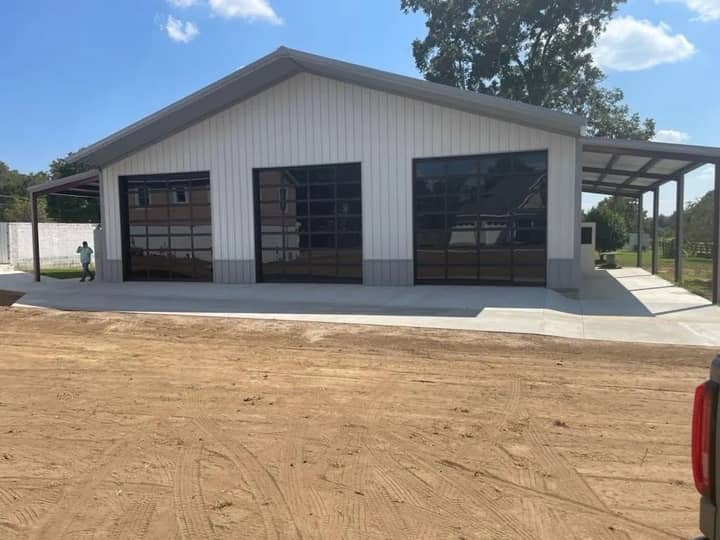 White metal shop with three glass garage doors and side lean-to